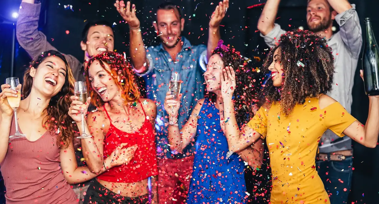 Friends celebrating under colorful confetti at a party